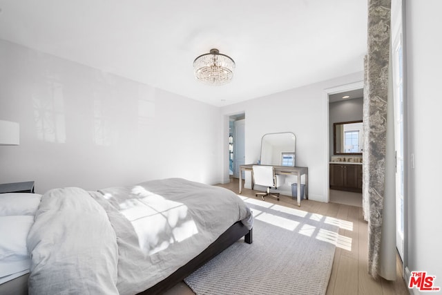 bedroom with a chandelier, connected bathroom, and light hardwood / wood-style flooring