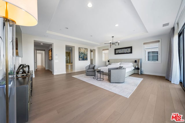 living room with a raised ceiling, a chandelier, and wood-type flooring