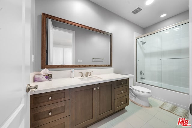 full bathroom with enclosed tub / shower combo, vanity, and toilet