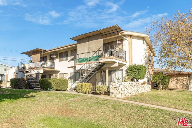 back of property with a balcony and a yard