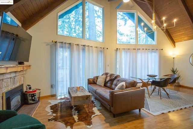 living room with a notable chandelier, a fireplace, light hardwood / wood-style floors, and high vaulted ceiling