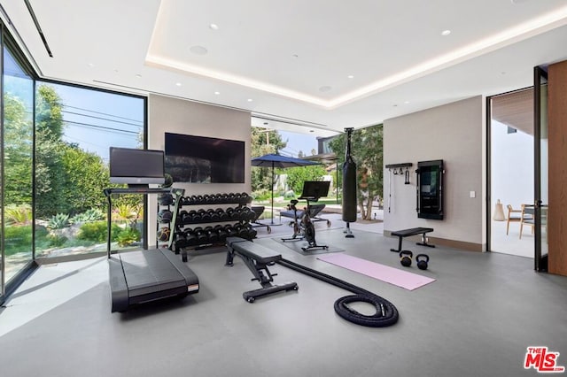 gym with a tray ceiling and expansive windows