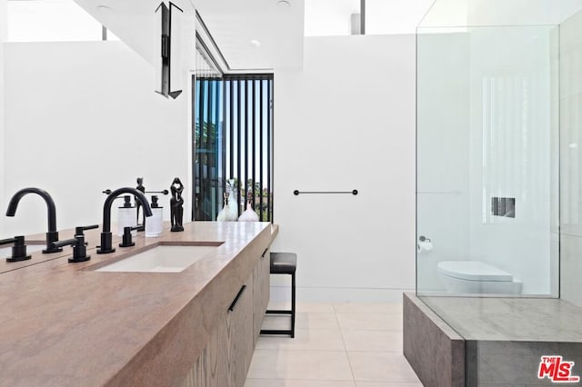 bathroom with a wealth of natural light, tile patterned floors, vanity, and toilet