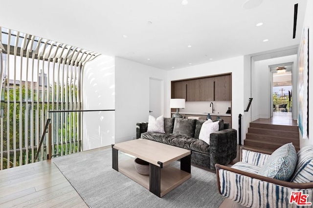 living room with light hardwood / wood-style floors, sink, and a wealth of natural light