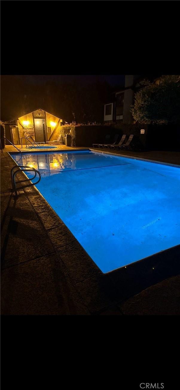 pool at night with a fenced in pool and a patio