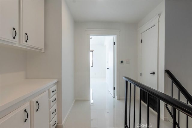 hallway with baseboards, an upstairs landing, and light tile patterned flooring