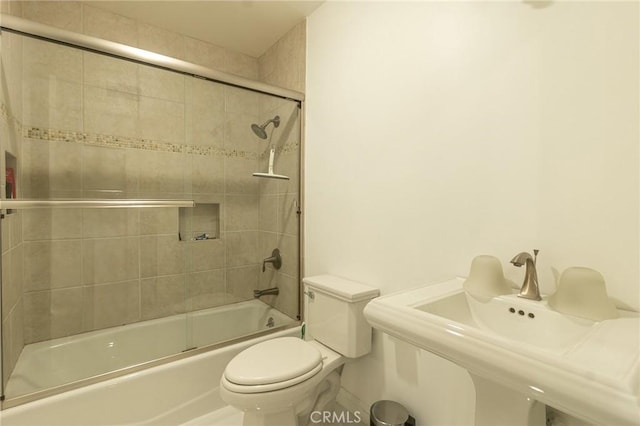 full bath featuring enclosed tub / shower combo, a sink, and toilet