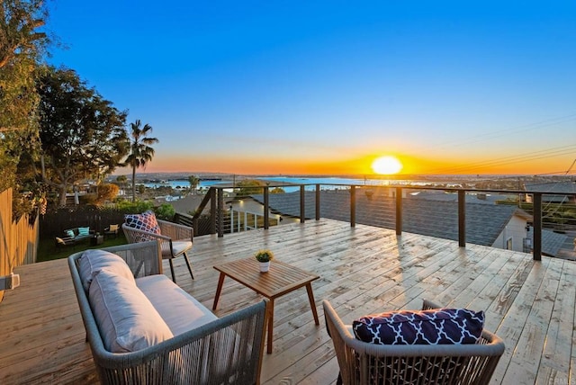 deck at dusk featuring a water view and outdoor lounge area