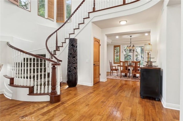 staircase featuring a high ceiling, wood-type flooring, and a notable chandelier