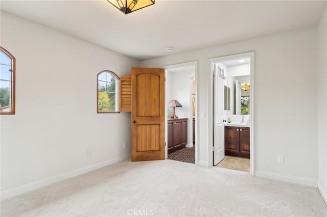 unfurnished bedroom with ensuite bath and light carpet