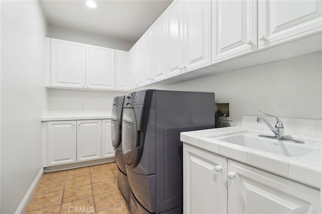 clothes washing area with washer and dryer, sink, and cabinets