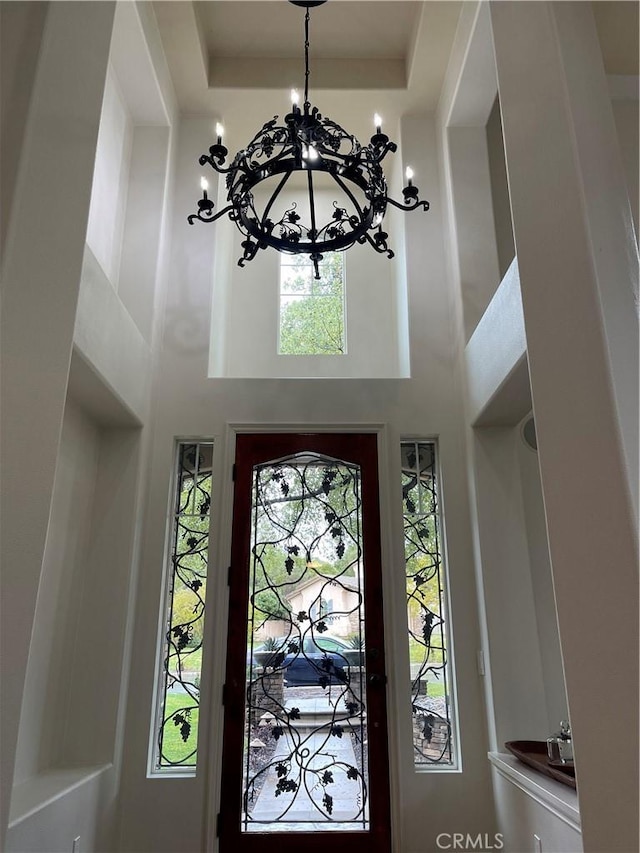 foyer featuring a notable chandelier, a tray ceiling, and a high ceiling