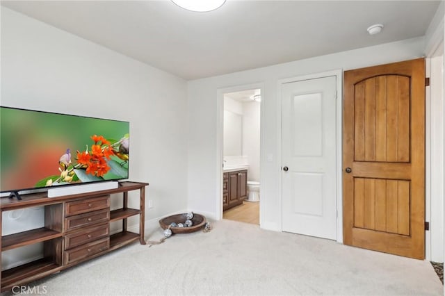 bedroom with light carpet and connected bathroom