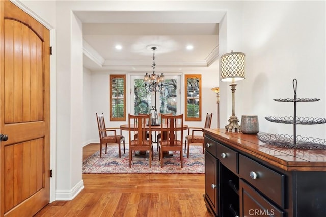 dining room with ornamental molding, an inviting chandelier, and light wood-type flooring