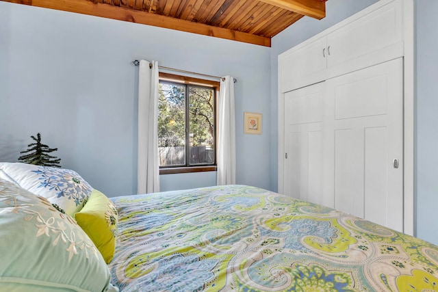 bedroom featuring beam ceiling, wooden ceiling, and a closet