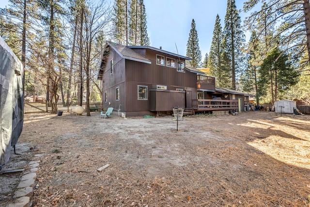 rear view of property featuring a shed and a deck