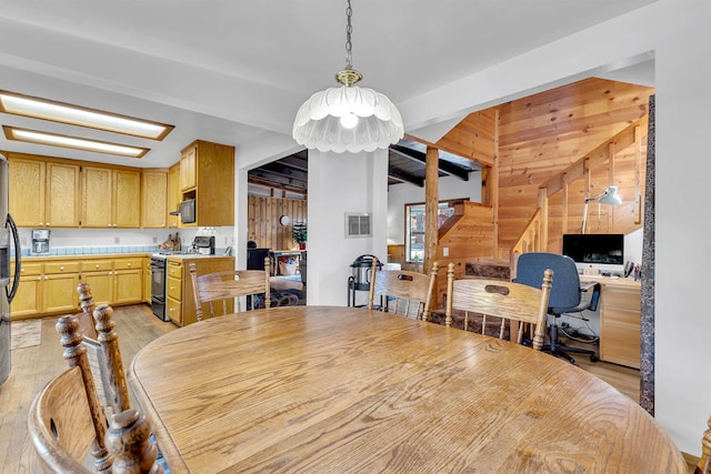 dining area with vaulted ceiling with beams, wood walls, light hardwood / wood-style flooring, and an inviting chandelier