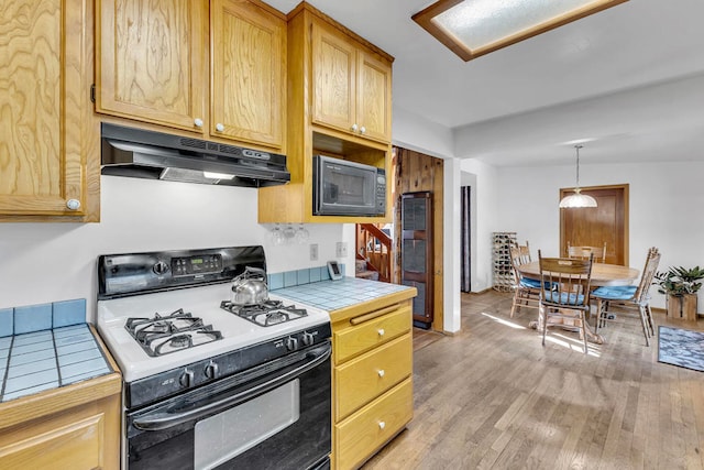 kitchen with black microwave, tile counters, light hardwood / wood-style flooring, range with gas cooktop, and pendant lighting