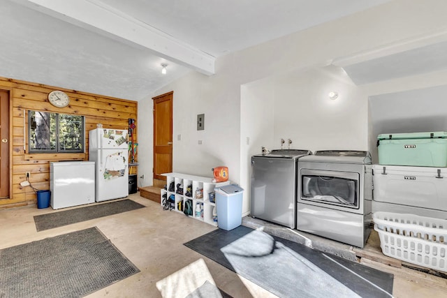 misc room featuring washing machine and clothes dryer, lofted ceiling with beams, wooden walls, and concrete flooring