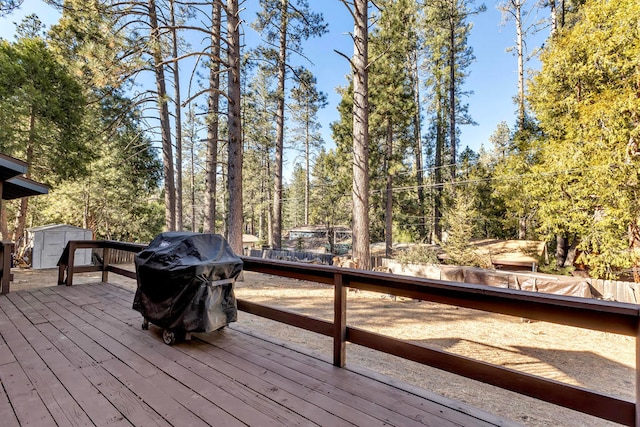 wooden deck featuring a storage shed and a grill