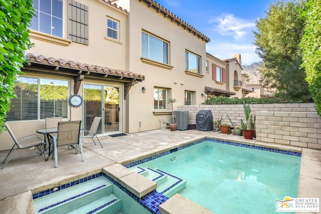 back of property featuring a pool with hot tub, central air condition unit, and a patio