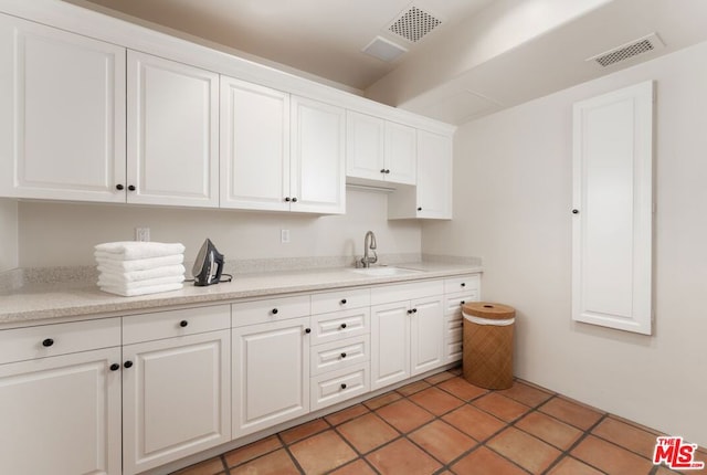 kitchen featuring white cabinetry, sink, and light tile patterned flooring