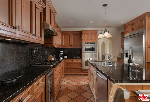 kitchen featuring beverage cooler, stainless steel appliances, dark stone countertops, decorative light fixtures, and decorative backsplash