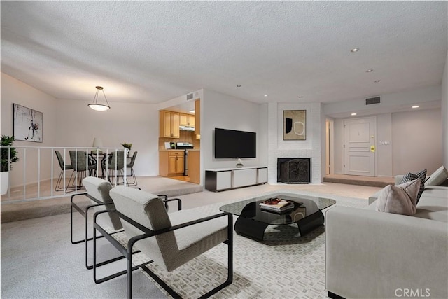 carpeted living room with a large fireplace and a textured ceiling