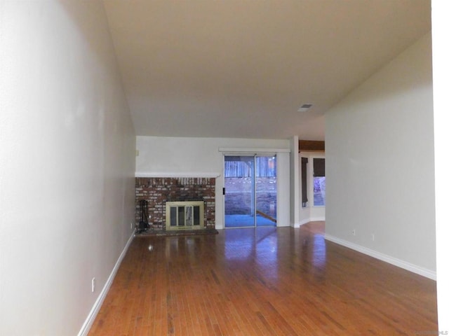 unfurnished living room with hardwood / wood-style floors and a brick fireplace