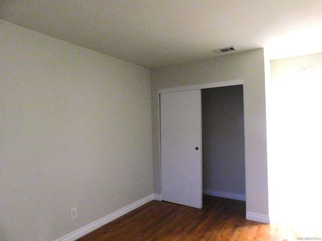 unfurnished bedroom featuring dark wood-type flooring and a closet