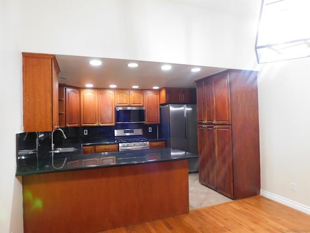 kitchen featuring kitchen peninsula, sink, light hardwood / wood-style floors, and appliances with stainless steel finishes