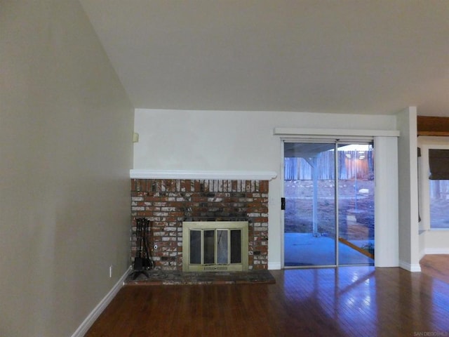 unfurnished living room featuring hardwood / wood-style floors and a brick fireplace