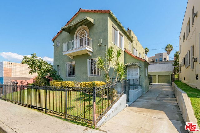 view of front of home featuring a front yard, a balcony, and a garage