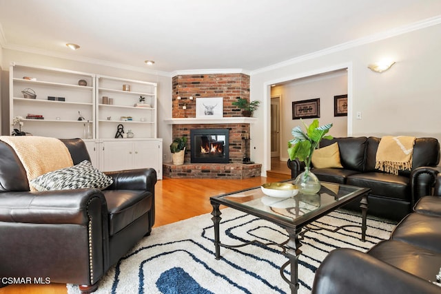 living room with light hardwood / wood-style floors, ornamental molding, and a brick fireplace