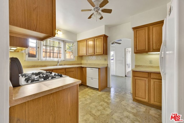 kitchen with stove, white refrigerator, sink, decorative backsplash, and ceiling fan