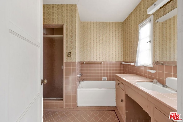 bathroom with tile patterned flooring, vanity, tile walls, and independent shower and bath