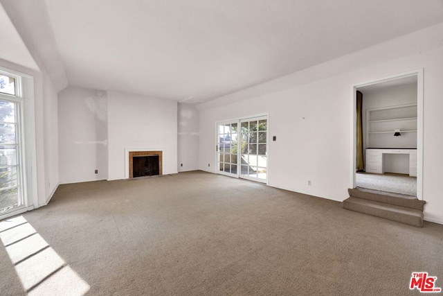 unfurnished living room featuring carpet and built in shelves