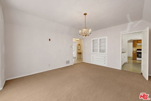 carpeted empty room featuring built in shelves and an inviting chandelier