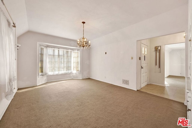 carpeted empty room featuring lofted ceiling and a notable chandelier