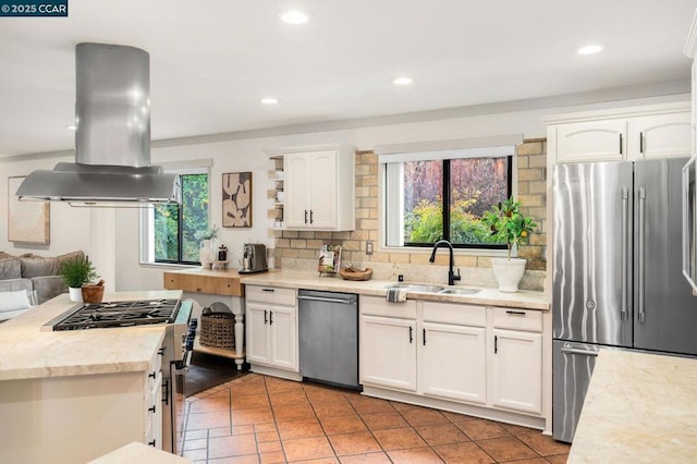 kitchen with sink, white cabinetry, high end appliances, island range hood, and decorative backsplash