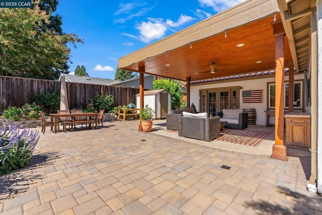 view of patio with ceiling fan, an outdoor living space, and a shed