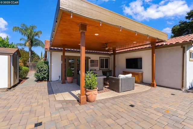 view of patio with an outdoor living space, ceiling fan, and a storage unit