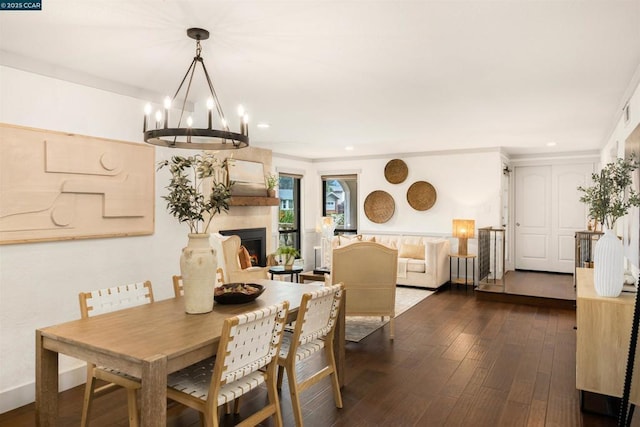 dining space with dark hardwood / wood-style flooring, a fireplace, and an inviting chandelier