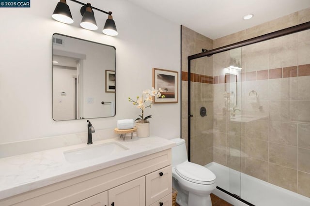 bathroom featuring vanity, toilet, and a shower with shower door