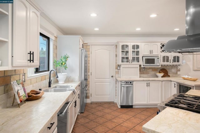 kitchen featuring sink, white cabinetry, island range hood, stainless steel appliances, and backsplash