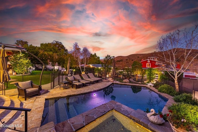 pool at dusk featuring a lawn, a patio area, and a mountain view