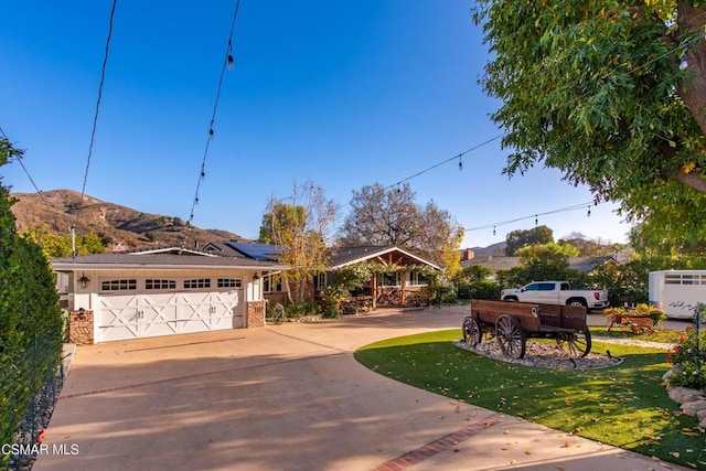 exterior space with a mountain view, solar panels, a garage, and a front yard