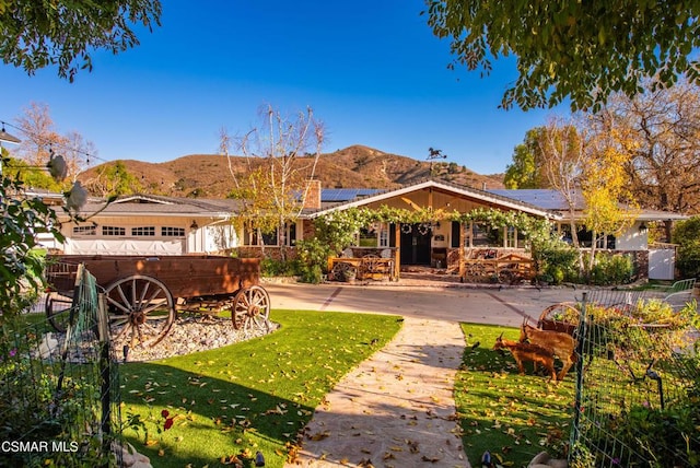 back of property featuring a mountain view, a yard, a garage, and solar panels