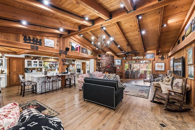 living room with beam ceiling, light hardwood / wood-style floors, wooden walls, wood ceiling, and ceiling fan with notable chandelier