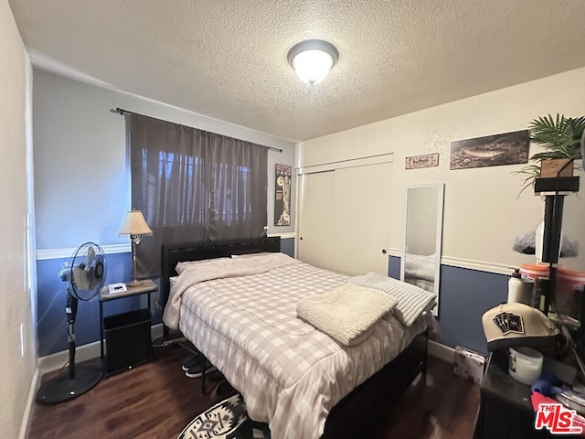 bedroom with a textured ceiling, dark hardwood / wood-style flooring, and a closet